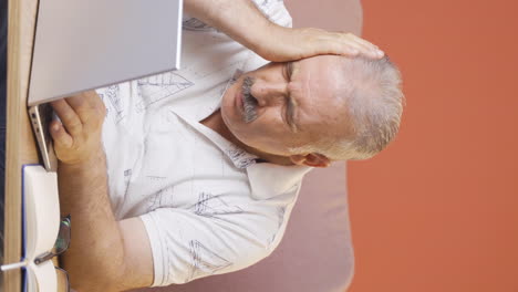 Vertical-video-of-Old-man-looking-at-laptop-gets-frustrated.